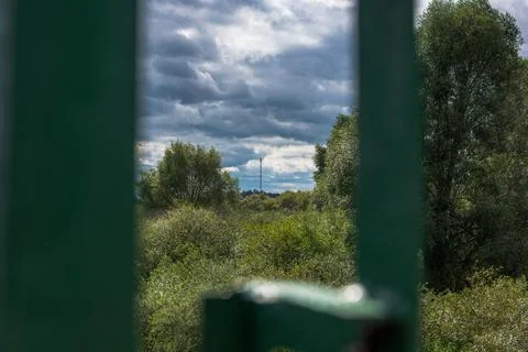 Framed view through green structural pillars toward deciduous forest canopy,  스톡 사진