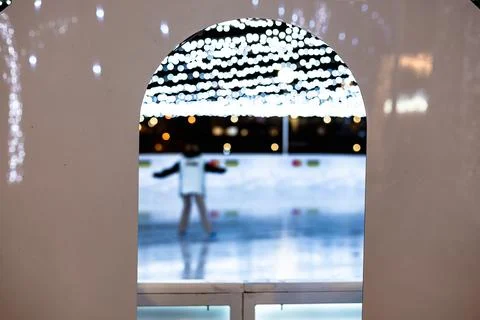 A framed view through a white archway to outdoor ice rink at night. Stock Photos
