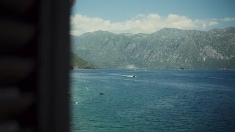 Framed window view of Bay of Kotor, Montenegro, boats and ridges Stock Footage 329412660