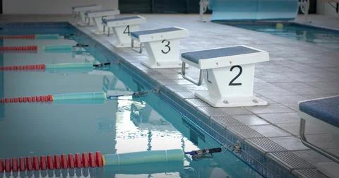 Framing starting block 2 sitting on deck in competition pool, lane ropes, poo Stock Photos