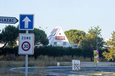 France, 10 August 2024 : Road signs near unique pyramid-shaped building and t Stock Photos