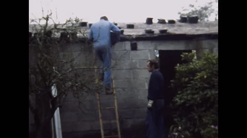 France 1974: bricklayer comes down the ladder carrying bricks Stock Footage 304663909