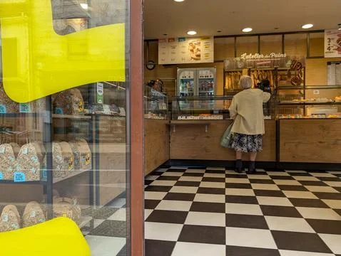 France, 24 August 2024 : Elderly woman picking baked goods inside a French ba Foto stock