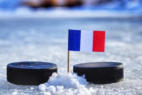 A France flag on toothpick between two hockey pucks.  A France will playing o Stock Photos