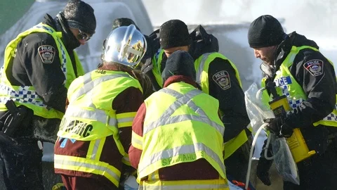 Frantic scene of paramedics and cops helping victim laying on stretcher in storm Stock Footage 125216938
