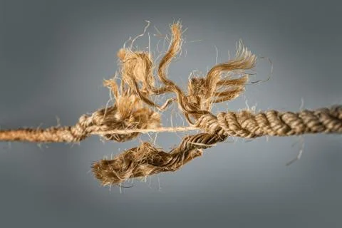 Frayed rope near to break on gray background Stock Photos