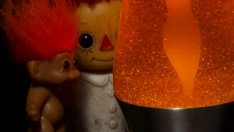Freaky and strange mood with a troll and doll staring at an orange lava lamp. Vídeos de archivo 134286443