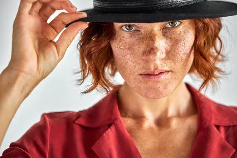 Freckled caucasian woman with short natural red haired in black hat Stock Photos