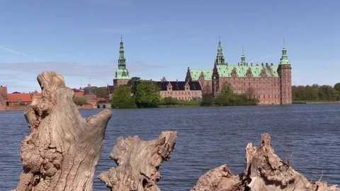 Frederiksborg Castle viewed over an old tree trunk and the castle lake 스톡 동영상 75459466