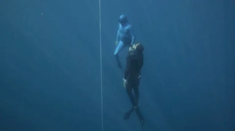 Free divers come up from a deep ocean dive Stock Footage