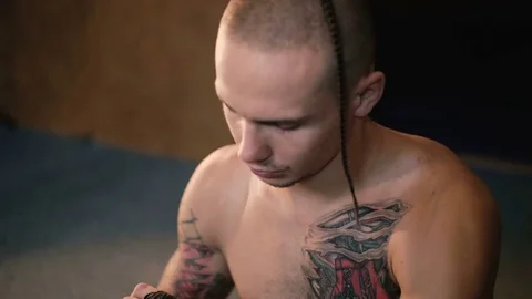 Free fighter wraps his hands with black hand wrap before the fight training. 4K Stock Footage