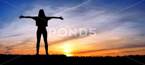 Free happy woman raising arms watching the sun in the background at sunrise Stock Photos