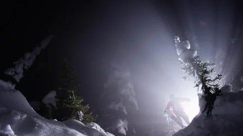 Free style skier jumping down the snowy mountain slope at night Stock Footage 116738201