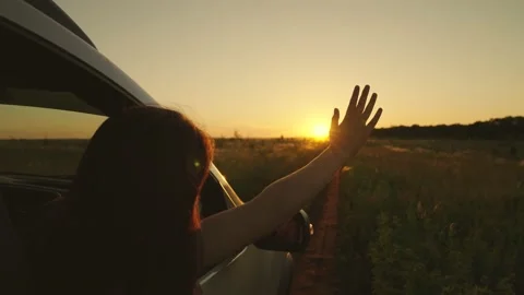 Free young girl waves her hand from car window, travels, catches sun glare with Stock Footage