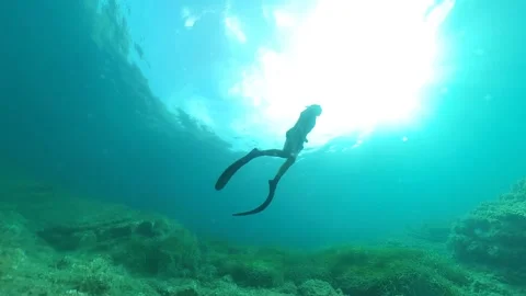 A freediver ascends from the seabed in a beam of light Video stock 199977912