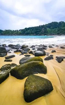 Freedom Beach rocks and waves beneath rain clouds Karon Phuket Thailand. Stock Photos