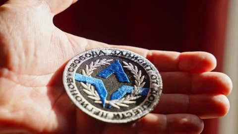 Freedom of Russia Legion patch held between fingers, highlighting its structure Stock Footage 304590142