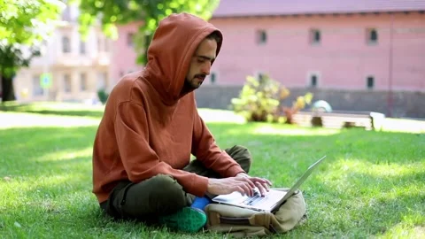 Freelance business man using modern laptop sitting in sunny green park enjoying Видео 139616654