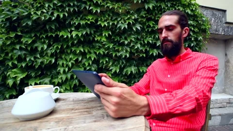 Freelance businessman using tablet device sitting in outdoor restaurant 動画素材 133593608