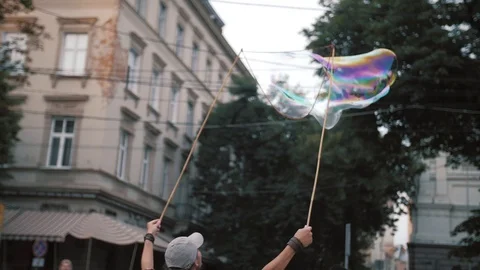 A freelance clown blowing hundreds of tiny, small and big bubbles at outdoor Stock Footage 104205601