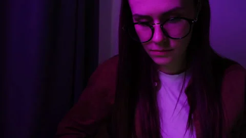 Freelance girl in eyeglasses with reflections using computer in neon red light Stock Footage 152476204