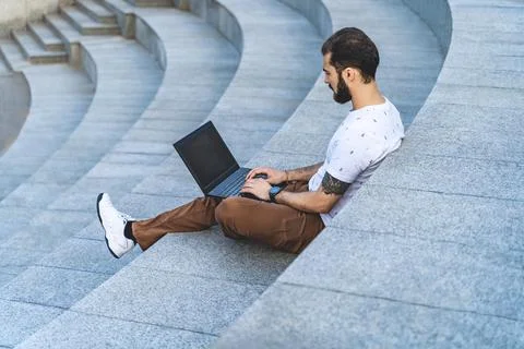 Freelance guy with laptop is working on steps. Remote worker typing on comput Stockfoto's