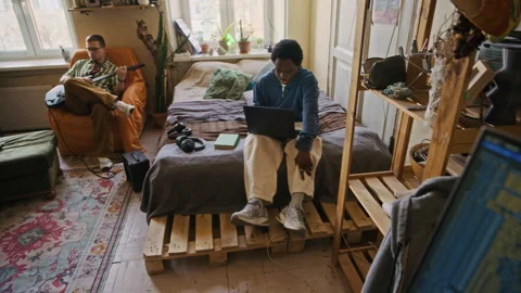 Freelance Programmer Working on Laptop while Roommates Resting with Guitar Stock-Footage 334802554