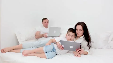 Freelance work allows family to be together father works on laptop in bed at Stock Footage 264020758