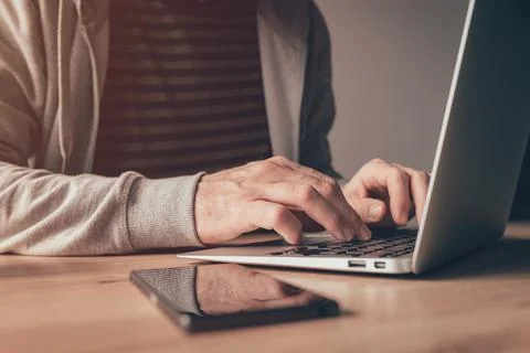 Freelance worker using laptop computer at home office desk Stock Photos