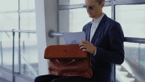 Freelancer in business suit checking on documents in his briefcase siting on Stock Footage 133595623