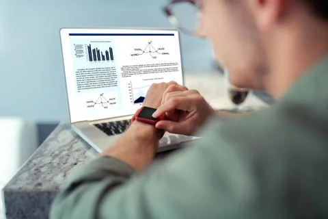 Freelancer checking time on smart watch while sitting near laptop Foto stock