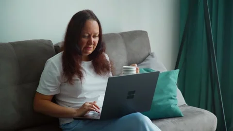 Freelancer with coffee and laptop on sofa Stock Footage 332322357