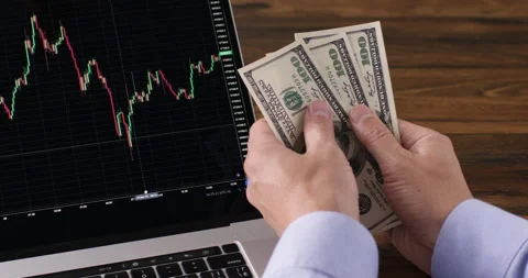 Freelancer counts money against graphs of cryptocurrency Stockbeeldmateriaal 230146460