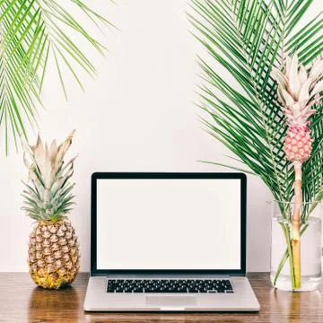 Freelancer desktop whith computer, palm branches and decorative pink pineappl Foto stock