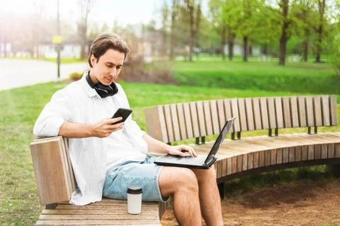 Freelancer doing remote work on a laptop outdoors. Man sitting on a park be.. Stock-Fotos