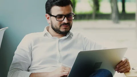 Freelancer in formal shirt sitting with computer and nodding to the camera Stock Footage 112989913