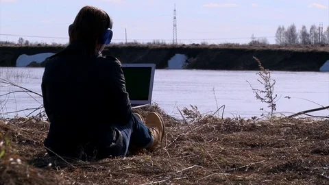 Freelancer girl using notebook, working outside in isolation on river shore Stock Footage 75686633