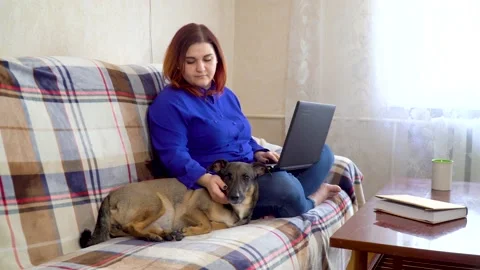 Freelancer girl working on a laptop while sitting on a sofa at home Stock Footage 134937338