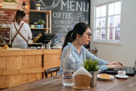 Freelancer in glasses using laptop sit at cafe 库存照片
