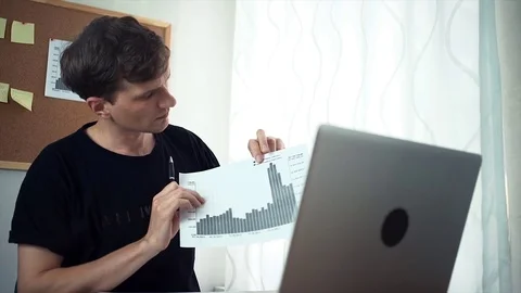 Freelancer having video call using laptop demonstrating printed analyzing graphs Stock Footage 79897958