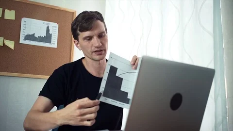 Freelancer having video call using laptop demonstrating printed analyzing graphs Video stock 79898109