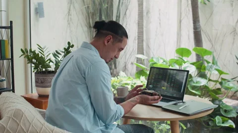 Freelancer Holding Small Snake while Analyzing Charts on Laptop at Home Office Stock Footage 302229900