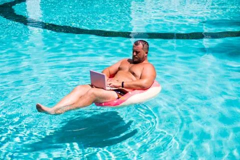 Freelancer with an inflatable ring in the water in the pool works on the Stock Photos