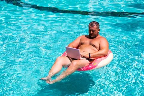 Freelancer with an inflatable ring in the water in the pool works on the Stock Photos