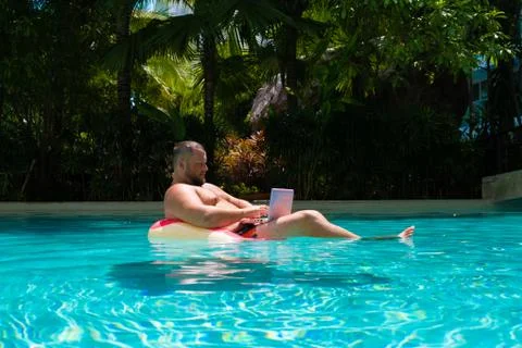 Freelancer with an inflatable ring in the water in the pool works on the Stock Photos