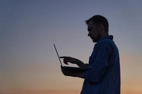 Freelancer male programmer silhouette using laptop outdoor at sunset Stock-Fotos