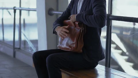 Freelancer man protects briefcase sitting and on bench at metro station, waiting Stock Footage 133594690