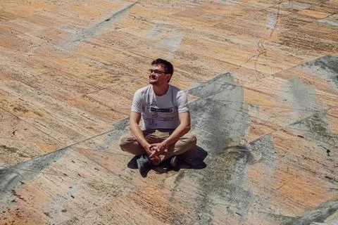 Freelancer man sitting on stone surface. Marble floor with people near concert Stock Photos
