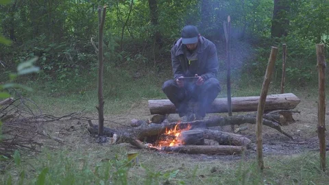 A freelancer man touch a tablet near tourist campfire in evening Video stock 90983497