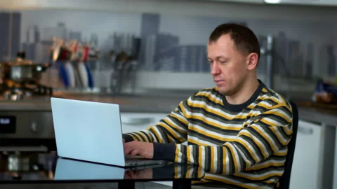 Freelancer man working at home sitting at the table,  of the kitchen Stock Footage 131874483